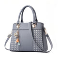 Gray handbag with decorative charms on a white background