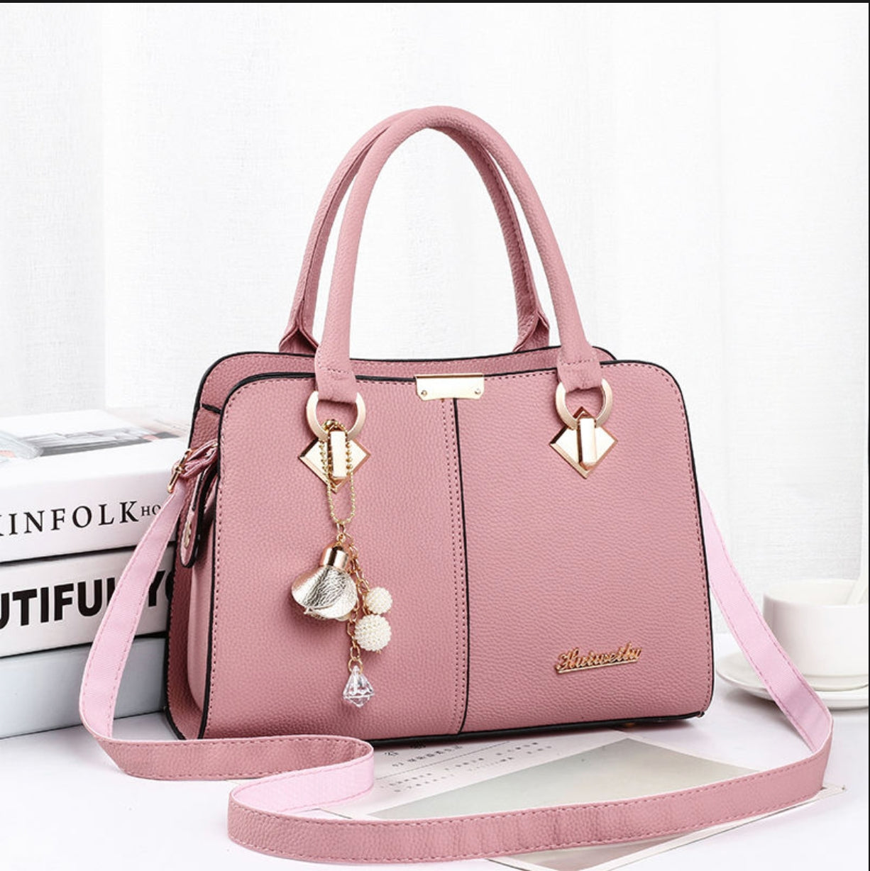 Pink handbag with decorative charm on a white background