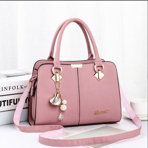 Pink handbag with decorative charm on a white background