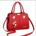 Red handbag with decorative charms on a white background
