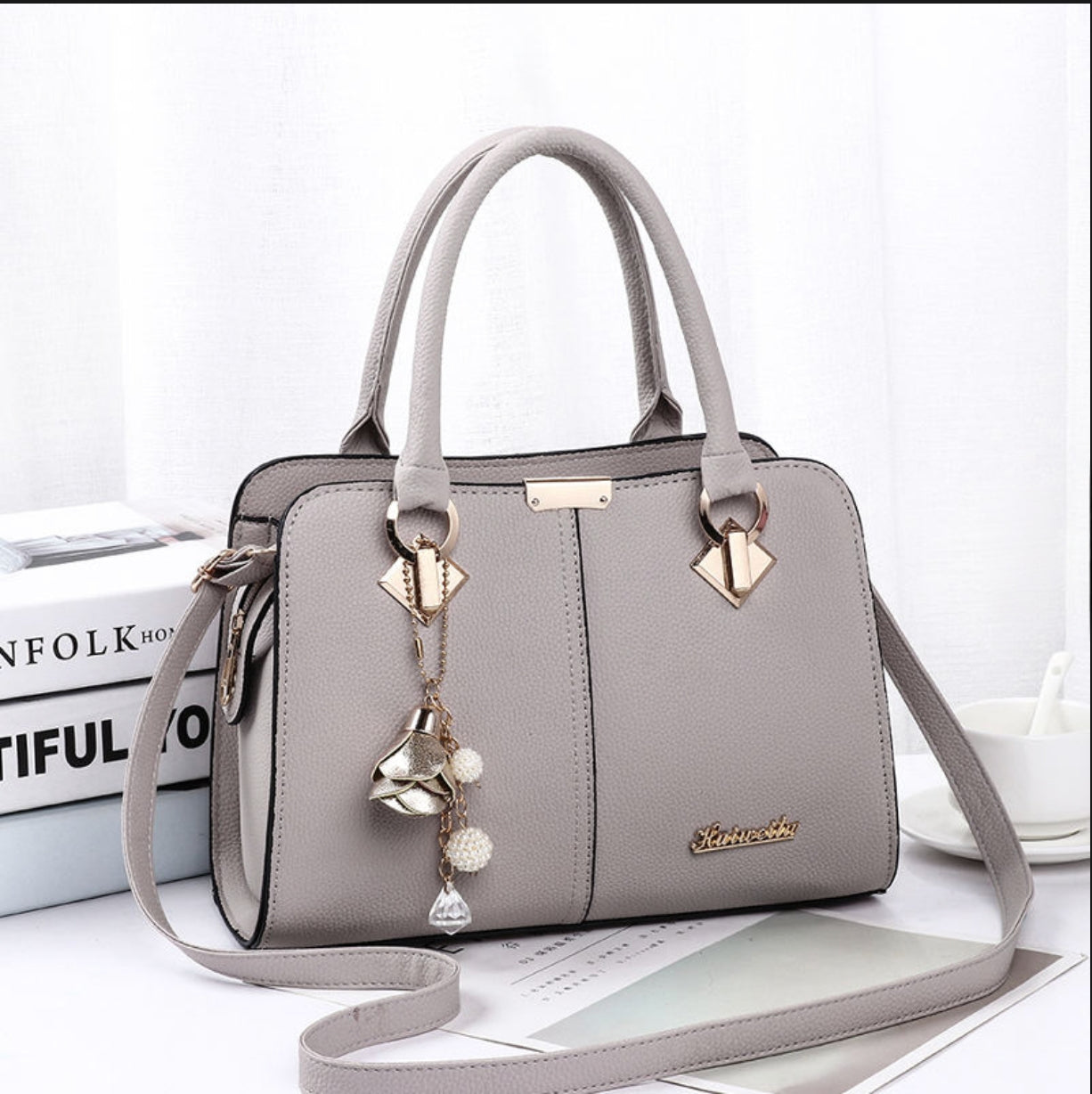 Gray handbag with decorative strap on a white surface