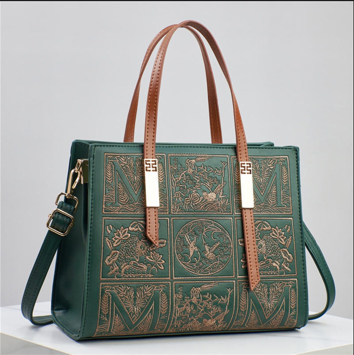Green handbag with brown leather straps on a light gray background