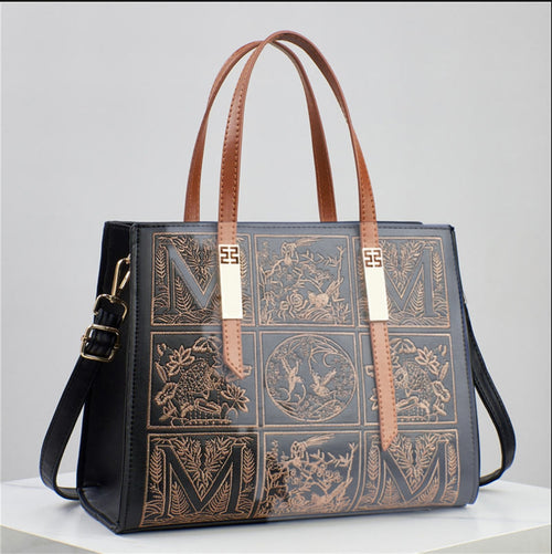 Designer handbag with embossed patterns and brown handles on a gray background
