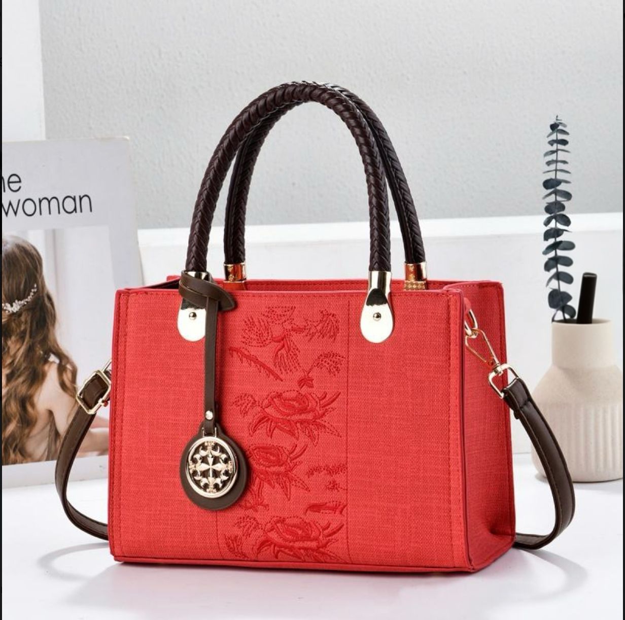 Red handbag with braided handles on a white surface