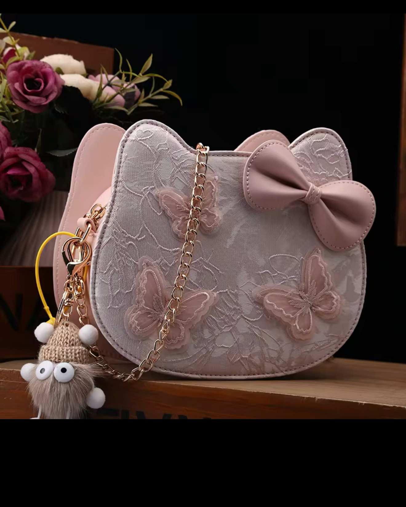 Pink handbag with butterfly design and bow on a dark background