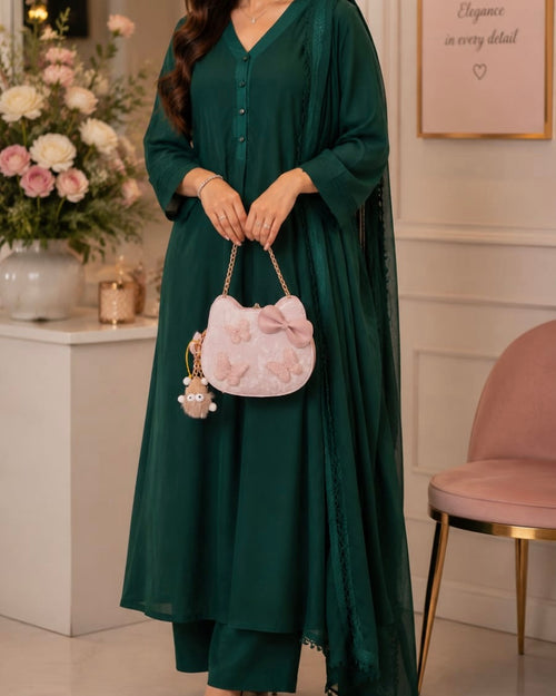 Woman in a green dress holding a pink handbag in an elegant room.