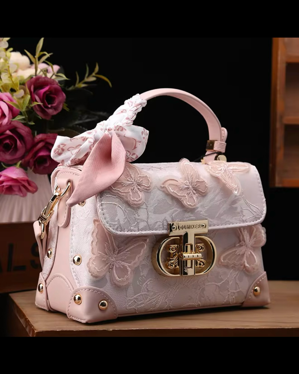 Pink lace handbag with a bow and butterfly details on a dark background
