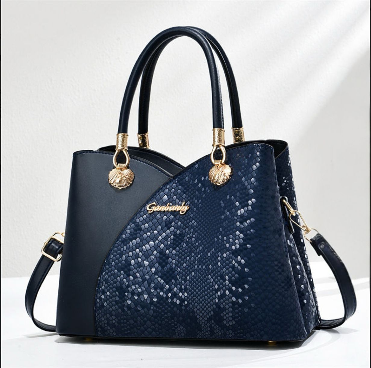 Navy blue handbag with gold accents on a light gray background