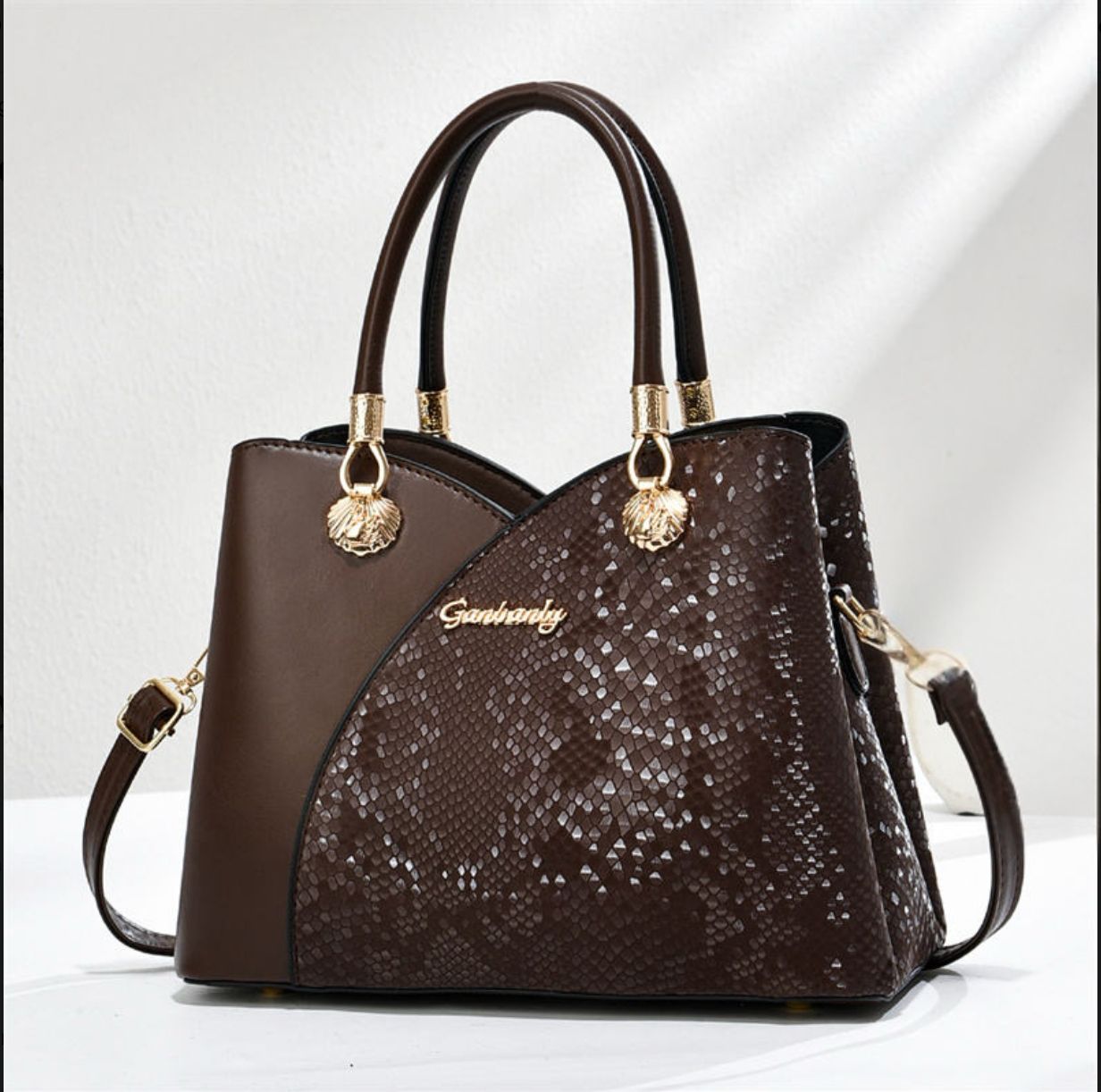 Brown handbag with gold accents on a white background