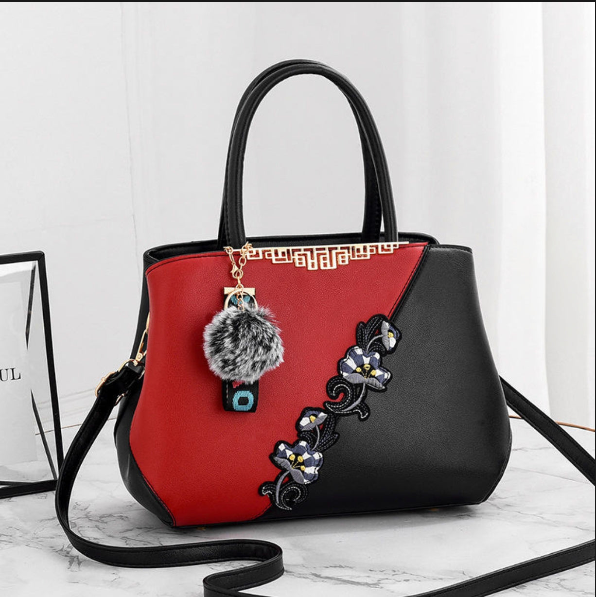 Black and red handbag with decorative elements on a light background